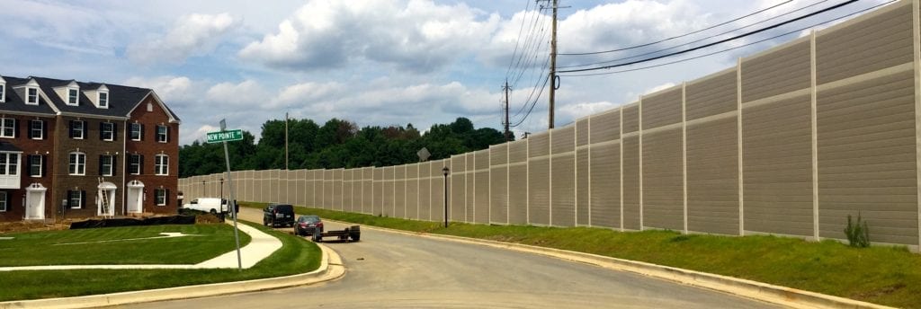 Wide view of noise barrier-wall with residential townhomes on left