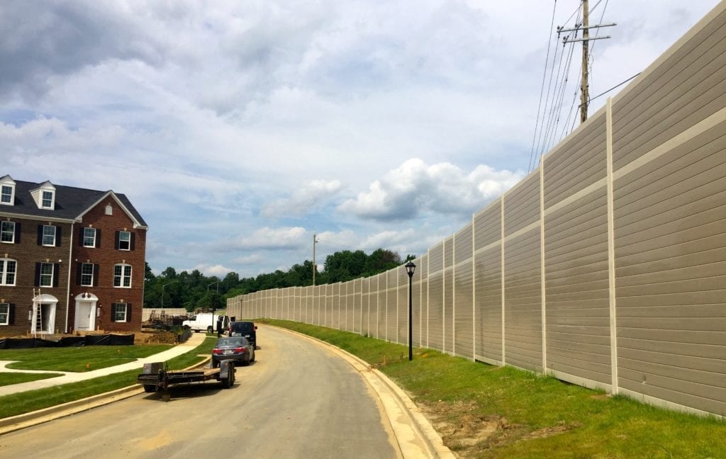 Wide view of gracefully-curving noise barrier wall with townhomes