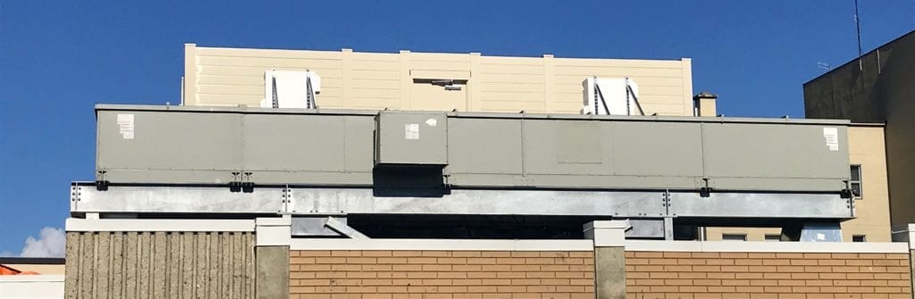 Ground view of rooftop-mounted sound barrier wall equipment enclosure