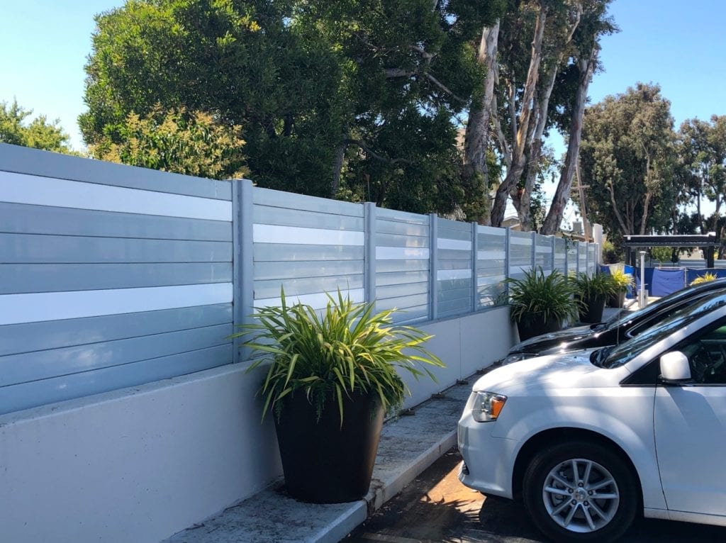 Cars parked next to sound barrier wall mounted to parking structure