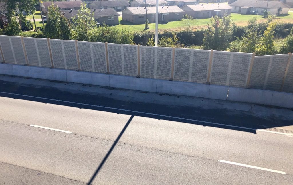 Overpass view of highway noise barrier wall with houses