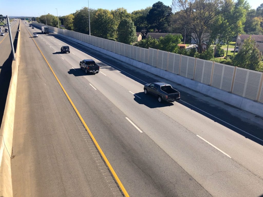 Overpass view of traffic passing highway noise barrier wall