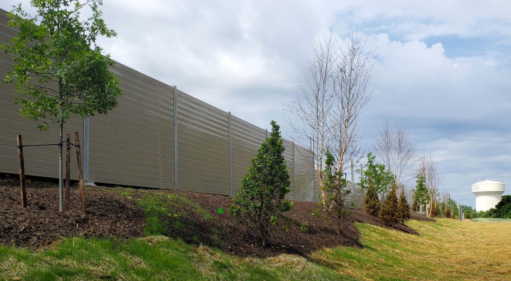 Wide view of distribution center noise barrier wall with landscaping