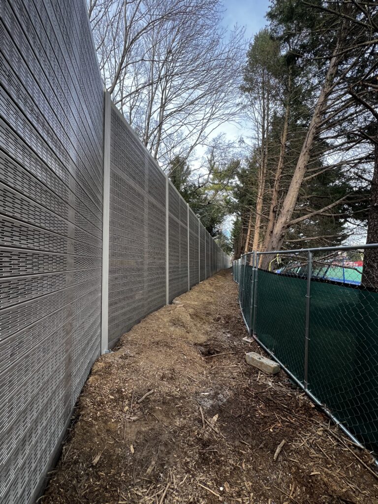 Detail view of noise barrier wall running through wooded area