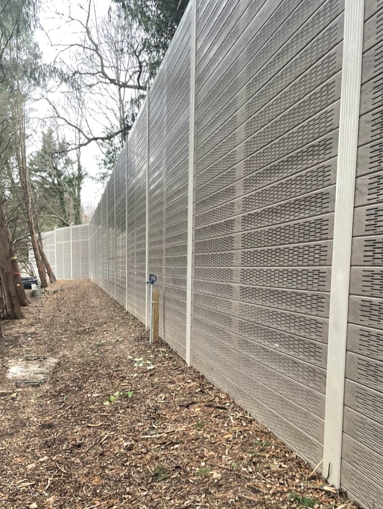 Angled view of noise barrier wall running through wooded area